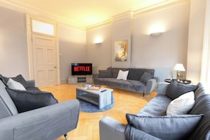 Ein modernes Wohnzimmer mit grauen Sofas, einem Couchtisch, einem Flachbildfernseher und einem Bild an der Wand.