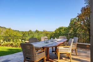 A patio with a table and chairs, a railing, and a view of greenery and hills. - Above Nashville Tranquility | Pool & Spa | 10 Acres | Gated (Nolensville)