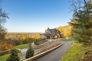 A large house with a driveway, surrounded by trees and a view of the landscape. - Above Nashville Tranquility | Pool & Spa | 10 Acres | Gated (Nolensville)