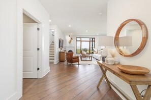 A spacious living area with a wooden floor, a large mirror, a sofa, and a coffee table. - Above Nashville Tranquility | Pool & Spa | 10 Acres | Gated (Nolensville)