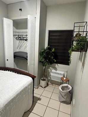 A bedroom with a bed, a wardrobe, a radiator, a potted plant, and a small table. - 2-bedroom apartment in beautiful San Juan with AC (San Juan)