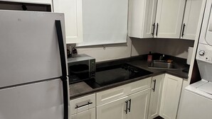 A kitchen with white cabinets, a black countertop, and a tiled floor. - 2-bedroom apartment in beautiful San Juan with AC (San Juan)