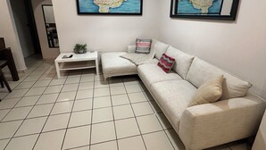 A living room with a sofa, a coffee table, a small table with a plant, and two framed maps on the wall. - 2-bedroom apartment in beautiful San Juan with AC (San Juan)