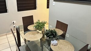 A dining area with a glass table, four chairs, and a potted plant. - 2-bedroom apartment in beautiful San Juan with AC (San Juan)