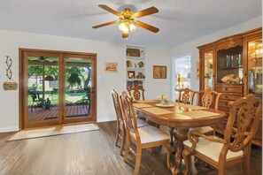 A dining area with a wooden table and chairs, a ceiling fan, and a view of a patio with outdoor furniture. - The Garden View / Near DFW Airport & AT&T stadium (Euless)