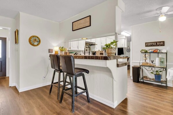 A kitchen with a bar area, a clock, and a coffee bar sign. - The Garden View / Near DFW Airport & AT&T stadium (Euless)