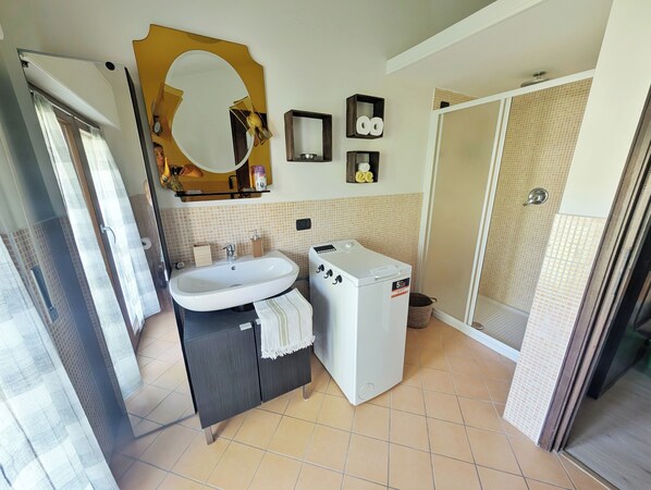 Ein Badezimmer mit Waschbecken, Spiegel, Handtuch und einer Waschmaschine.
