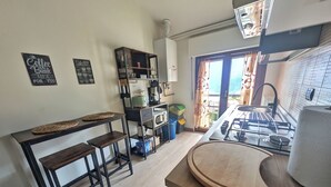 Una cocina con estufa a gas, taburetes de madera, una cafetera y vistas al exterior.