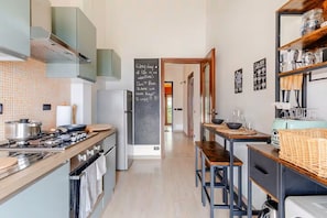Une cuisine moderne équipée d’une cuisinière à gaz, d’appareils électroménagers en acier inoxydable, d’un tableau noir avec des inscriptions et d’une machine à café.