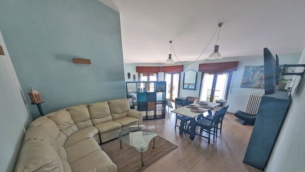 Una sala de estar con un sofá color crema, una mesa de centro de vidrio y un comedor con mesa y sillas.