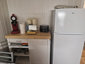 A kitchenette with a coffee maker, toaster, and refrigerator.