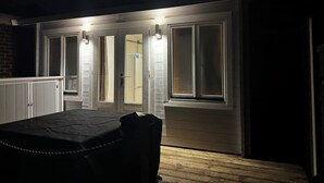 Pimeä huone, jossa on pöytä ja tuoleja, peilillä varustettu ovi ja valaisin oven yläpuolella.