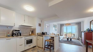 Una cocina moderna con una isla central, un área de comedor con vistas y un espacio de estar con balcón.