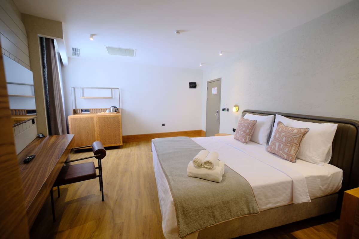 A hotel room with a bed, a desk, and a chair.