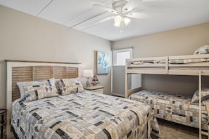Ein Schlafzimmer mit Etagenbett, einem Queensize-Bett, Deckenventilator und einem gerahmten Kunstwerk an der Wand.