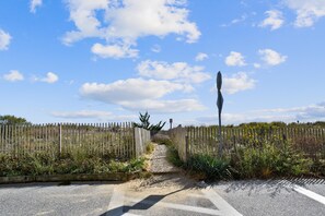Ein Kiesweg, der durch einen Holzzaun mit Vegetation an beiden Seiten führt.