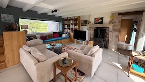 Ein modernes Wohnzimmer mit einer Sofagarnitur, einem Fernseher, einem Kamin und einem Bücherregal.