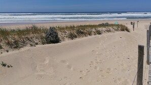 Ein Strand mit Sand, Wellen und einem Holzzaun.