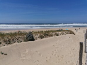 A beach with sand, waves, and a wooden fence. - Charming mobile home with all comforts (Saint-Julien-en-Born)