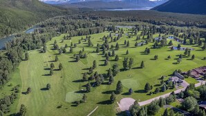 A golf course with a lake, mountains, and a clear sky.