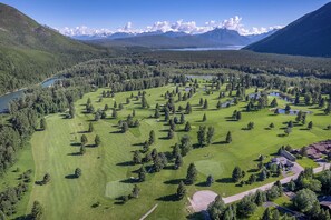 A golf course with a lake, mountains, and a clear sky.
