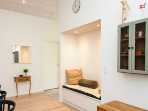 A room with a bench, a wooden cabinet, a clock, and a small table with a plant. - 5 Star Holiday Home in Farvang (Farvang)