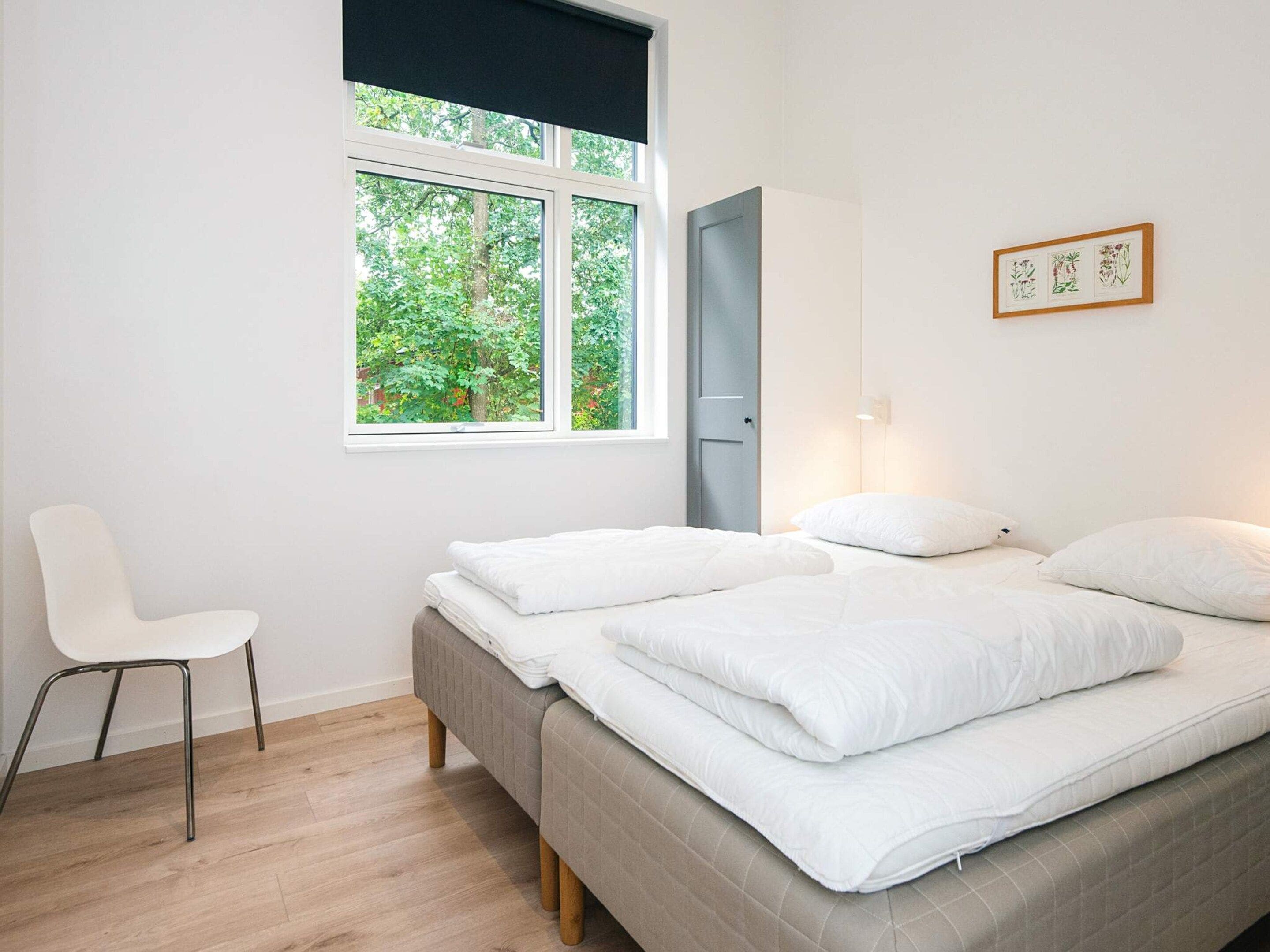 Une chambre à coucher avec un lit, une chaise, une fenêtre et une porte.