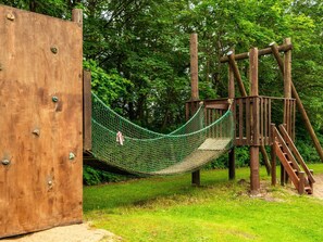 Eine Holzspielkonstruktion mit Netzschaukel und Rutsche.