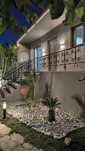 Ein modernes Haus mit einem Kiesweg, einem Metallgeländer und Topfpflanzen.