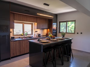 Eine moderne Küche mit Holzausstattung, einer großen Kochinsel mit Barhocker, einem eingebauten Backofen und einem Fenster für natürliches Licht.