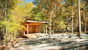 A wooden cabin with a porch, surrounded by a forest.