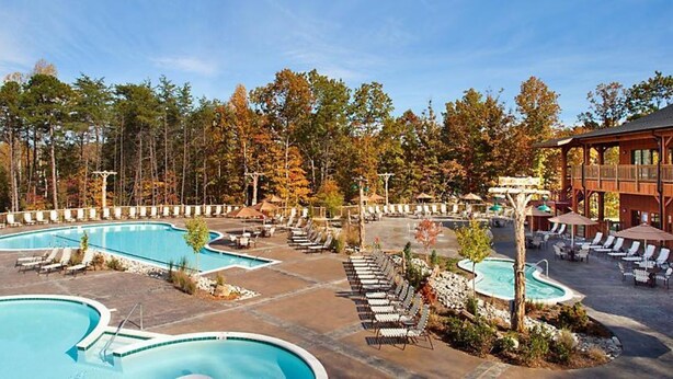 A resort with multiple swimming pools, lounge areas, and a wooden building.