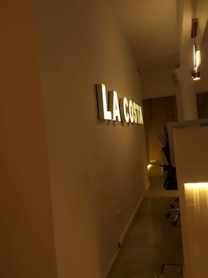 Ein Flur mit einem Schild mit der Aufschrift 'LA COSTA' und einem modernen Innenarchitekturstil.
