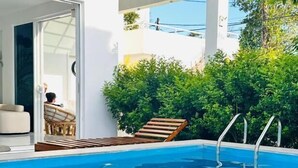 A swimming pool with clear water, a lounge chair, and a covered seating area. - La Costa Hotel (Seeduwa)