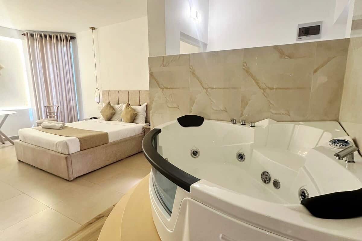 Uma casa de banho moderna com uma banheira grande, um sofá e uma janela com cortinas.