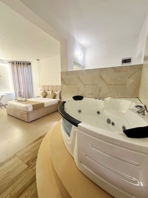 Ein modernes Badezimmer mit einer großen Badewanne, einer Couch und einem Fenster mit Vorhängen.