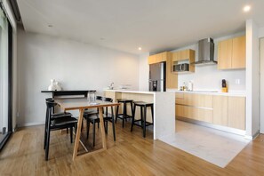 A modern kitchen with a central island, bar stools, and a dining table. - w Charming 1BR w/ AC in the Heart of Roma Sur (Mexico City)