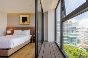 A modern hotel room with a large bed, a bedside table, a lamp, and a view of the city through large windows. - w Charming 1BR w/ AC in the Heart of Roma Sur (Mexico City)