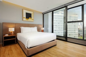 A modern hotel room with a large bed, two bedside tables with lamps, a framed artwork above the bed, and a large window offering a city view. - w Charming 1BR w/ AC in the Heart of Roma Sur (Mexico City)