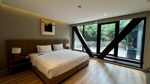 Una camera da letto moderna con un letto grande, lampade ai comodini, un quadro incorniciato e una vista attraverso ampie finestre.