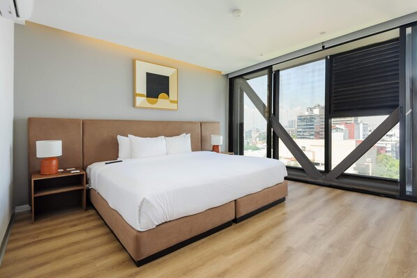 A modern hotel room with a large bed, a city view through floor-to-ceiling windows, and a framed artwork on the wall. - w Stunning 1BR w/ AC in the Heart of Roma Sur (Mexico City)