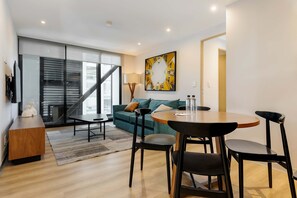 A modern living room with a sofa, a dining table with chairs, a staircase, and a large window. - w Stunning 1BR w/ AC in the Heart of Roma Sur (Mexico City)