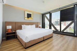 A modern hotel room with a large bed, a nightstand, a lamp, a framed picture, and a large window with a city view. - w Stunning 1BR w/ AC in the Heart of Roma Sur (Mexico City)