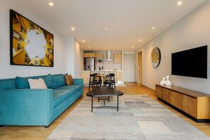 Ein modernes Wohnzimmer mit einem Türkis-sofa, einem Esstisch und einer Küche im Hintergrund.