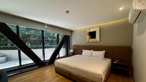 A modern hotel room with a large bed, a nightstand, a wall-mounted mirror, and a window with a view of greenery. - w Pleasant 1BR w AC in the Heart of Roma Sur (Mexico City)