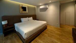 A modern hotel room with a bed, bedside table, wall-mounted air conditioning unit, and a door. - w Pleasant 1BR w AC in the Heart of Roma Sur (Mexico City)