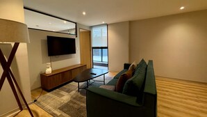 A modern living room with a flat-screen TV, a sofa, a coffee table, and a lamp. - w Appealing 1BR w AC in the Heart of Roma Sur (Mexico City)