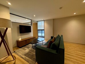 A modern living room with a flat-screen TV, a sofa, a coffee table, and a lamp. - w Appealing 1BR w AC in the Heart of Roma Sur (Mexico City)