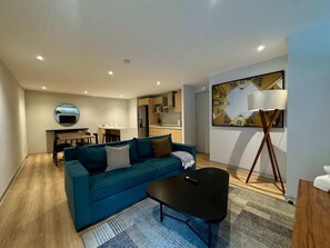 A modern living room with a teal sofa, a black coffee table, and a floor lamp. - w Appealing 1BR w AC in the Heart of Roma Sur (Mexico City)