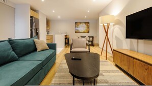 A modern living room with a sofa, a coffee table, a TV, and a dining area in the background. - w Deluxe 1BR w/ AC in the Heart of Roma Sur (Mexico City)